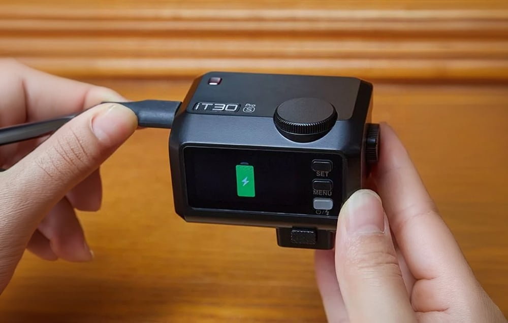 Czarna lampa błyskowa Godox iT30Pro S podłączona do przewodu USB-C podczas ładowania
